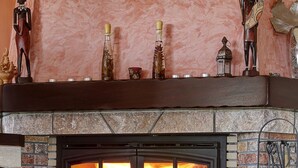 Une cheminée avec un foyer en briques, une étagère ornée d’objets décoratifs et un feu qui crépite à l’intérieur.