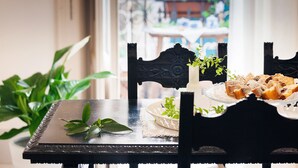 A dining table with a plate of food, a potted plant, and a chair.