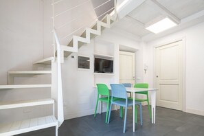 Un intérieur moderne avec un escalier, un coin repas avec des chaises et un téléviseur.