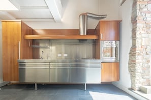 Une cuisine moderne dotée d’appareils électroménagers en acier inoxydable, de meubles en bois et d’un mur d’accent en pierre.