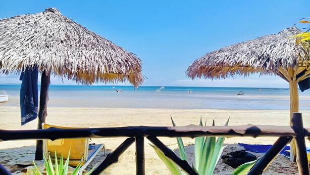 A beach with thatched umbrellas and a clear view of the ocean. - Tropical Paradise Nosy Be (Nosy Be)
