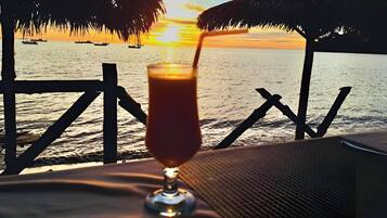 A sunset view from a balcony with a drink on a table.