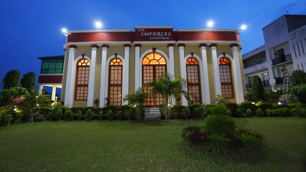 Un edificio con un cartel que dice "The Imperial Kushinagar". Presenta una fachada simétrica con ventanas arqueadas y una entrada central.
