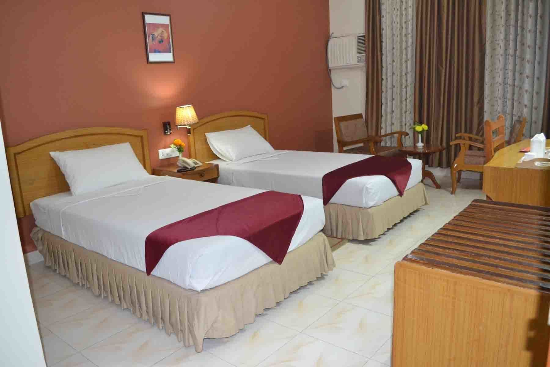 A hotel room with two beds, a desk, and a chair.