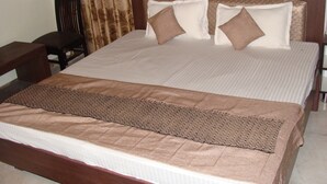 Un lit bien fait, avec une couverture marron et des oreillers, une tête de lit en bois et une table de chevet avec une lampe.