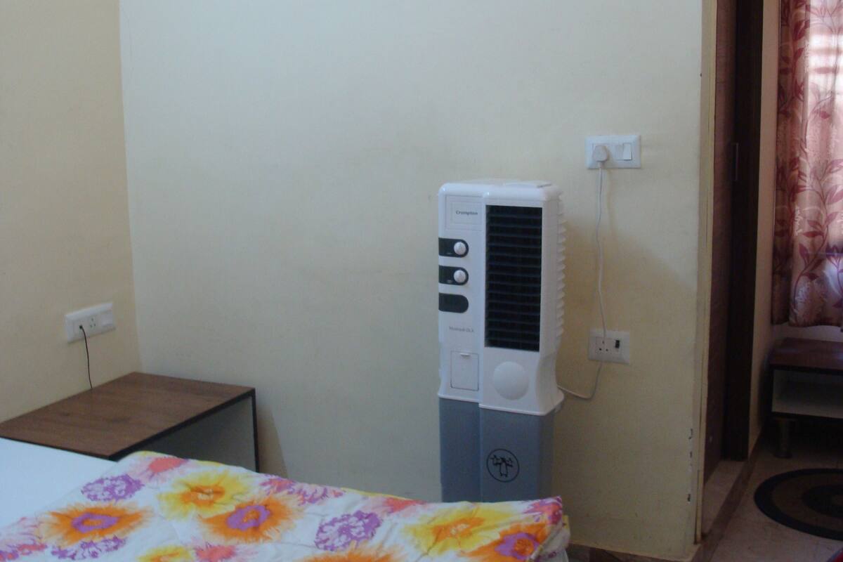 Une pièce comprenant un lit, une petite table, un radiateur et une porte avec un rideau.