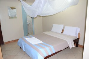A bed with a white canopy, a blue and beige striped bedspread, and a white pillow. - Starehe link hotel (Nairobi)