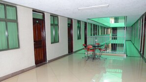 A spacious corridor with a green railing, a small table with chairs, and a door marked "S1". - Starehe link hotel (Nairobi)