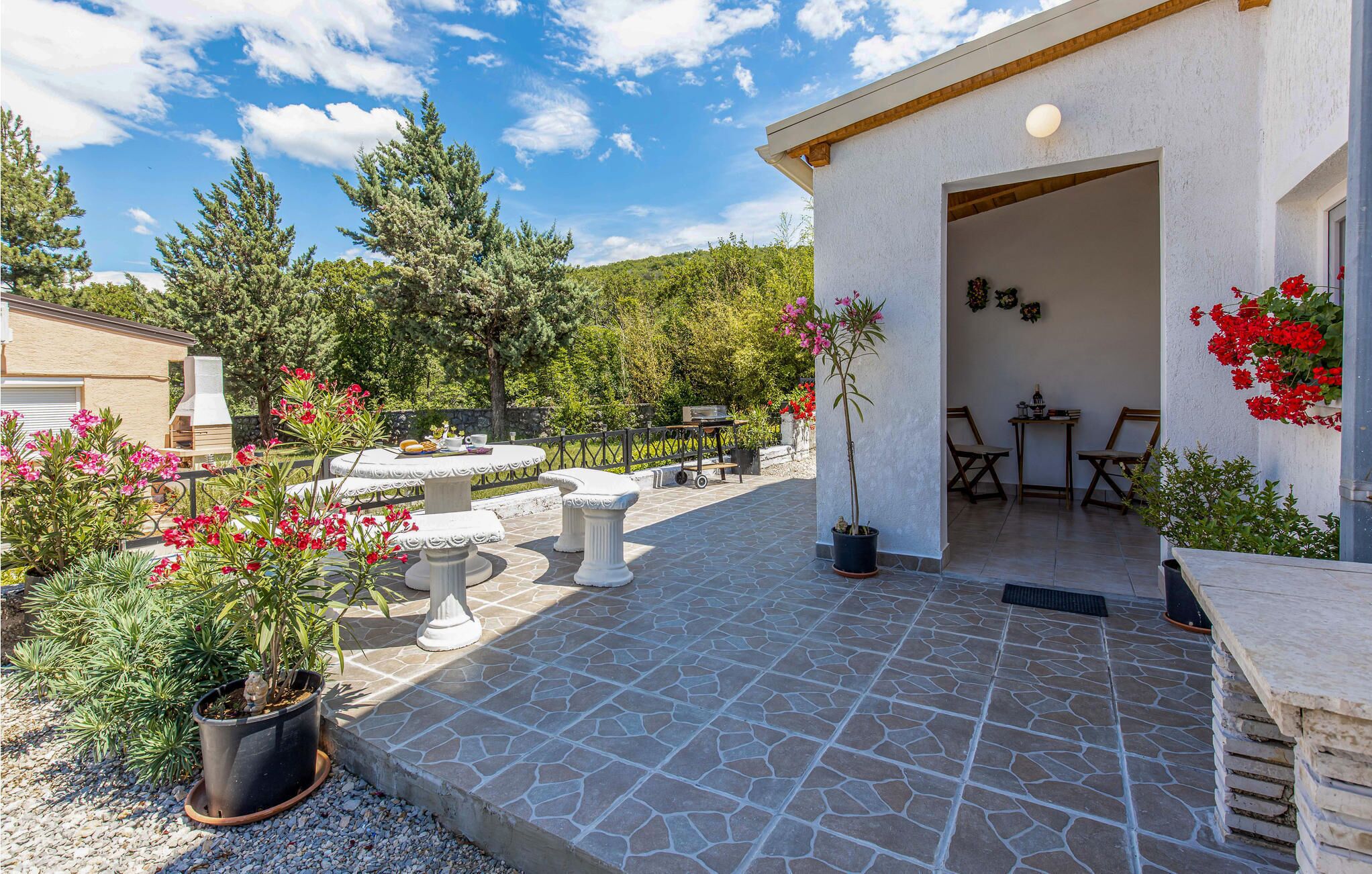 Un patio con suelo de piedra, mobiliario exterior y plantas en macetas.