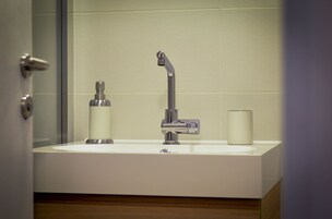 Un baño con lavamanos blanco, grifo cromado y dispensador de jabón.