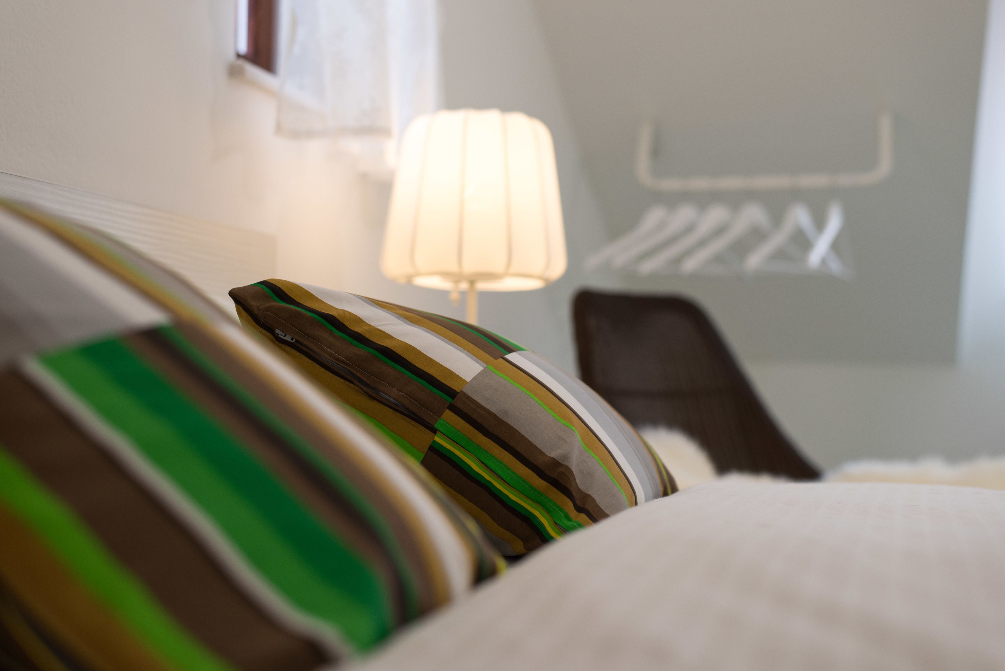 Ein Hotelzimmer mit einem Bett, Kissen, einer Lampe und einem Sessel.