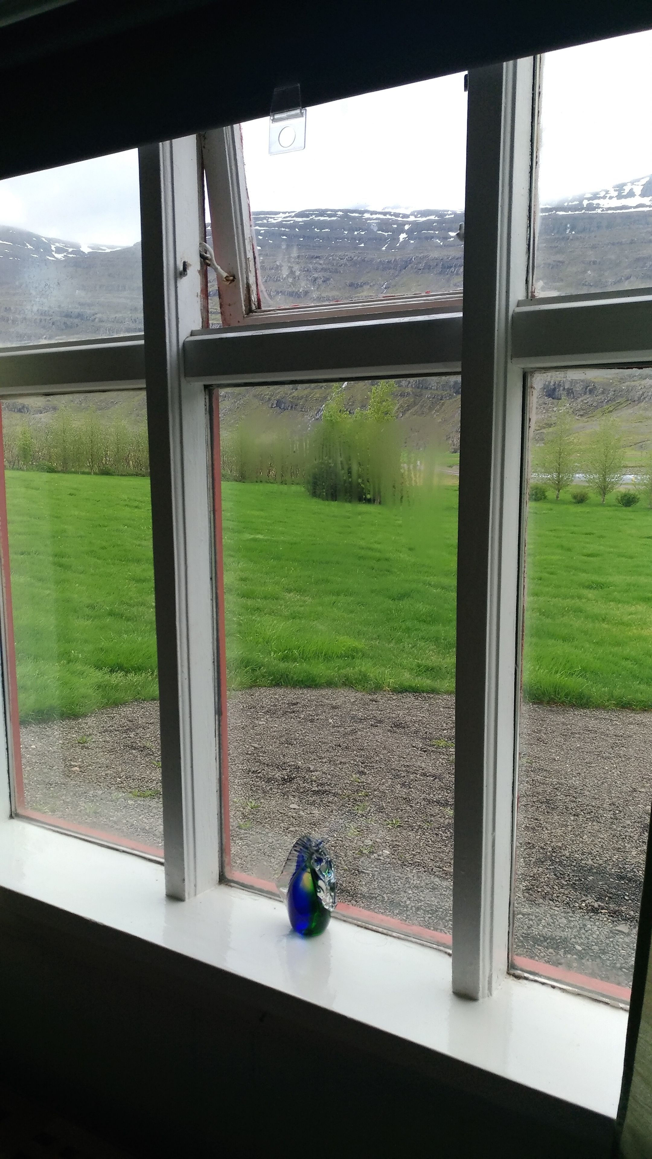 Una ventana con vistas a un campo verde y un camino de grava.