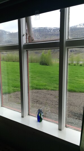 A window with a view of a green field and a gravel path. - Fossardalur Guesthouse - Hostel (Djupivogur)