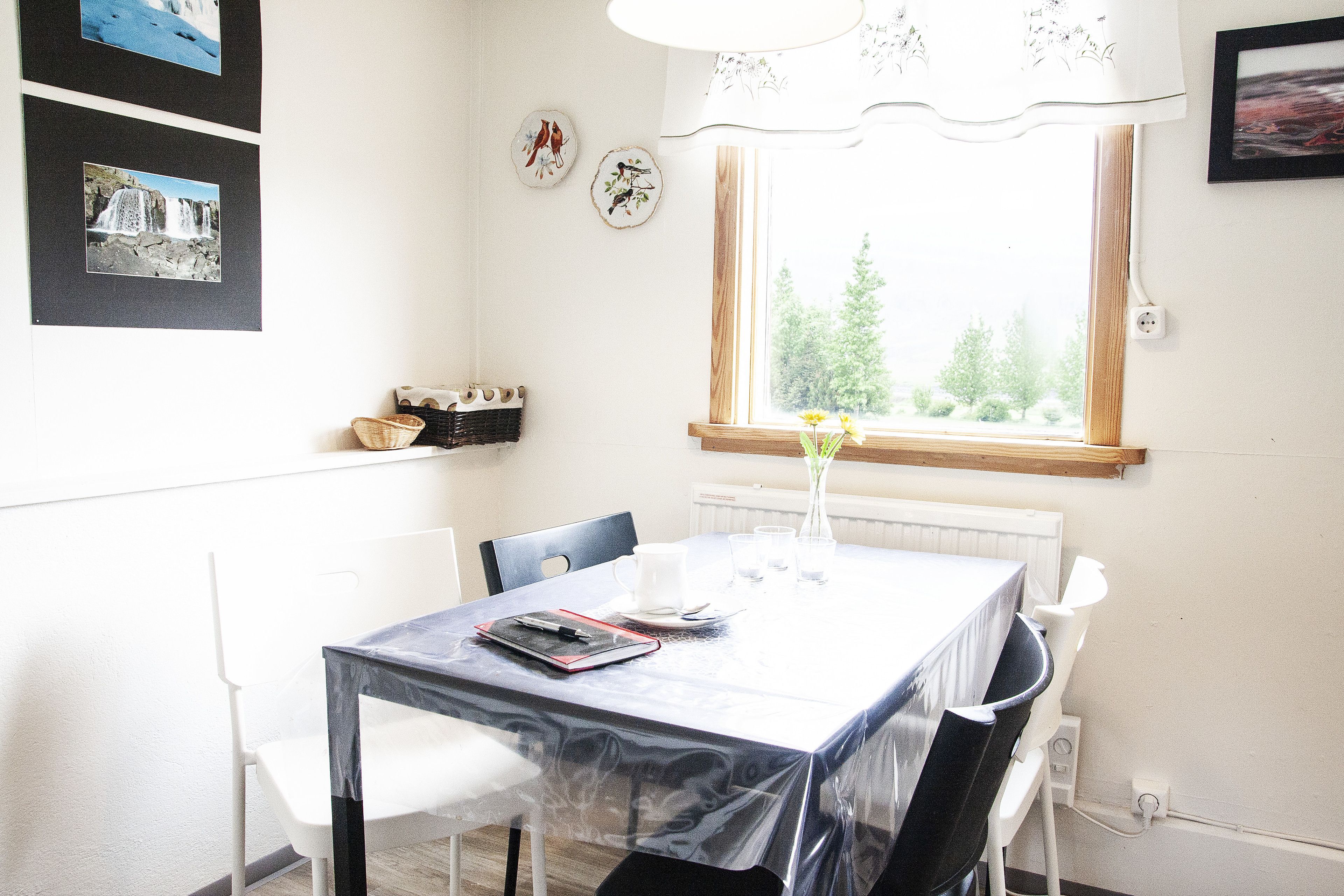 A dining area with a table, chairs, a vase with flowers, and wall-mounted pictures.