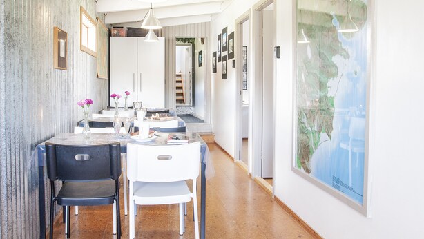 A dining area with a table set for two, chairs, and a vase with flowers. - Fossardalur Guesthouse - Hostel (Djupivogur)