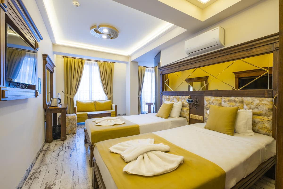 A hotel room with two beds, a wooden headboard, a ceiling light, and an air conditioning unit.