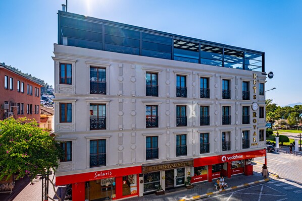 A hotel with a modern upper floor and a classic lower floor, featuring a Vodafone store and a restaurant named 'Solis'. - Reis Royal Hotel (Fethiye)