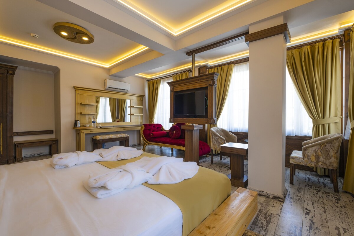 A hotel room with a large bed, a TV, a desk, and a chair.