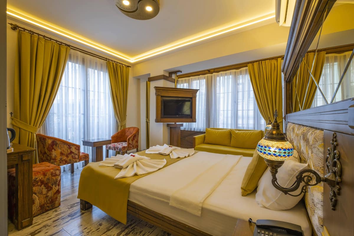 A hotel room with a bed, a sofa, a television, and a lamp.