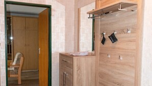 Una habitación con un banco de madera, un archivador pequeño y un perchero.