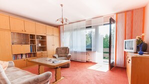 Una sala de estar con un sofá, un sillón, armarios de madera y un televisor.