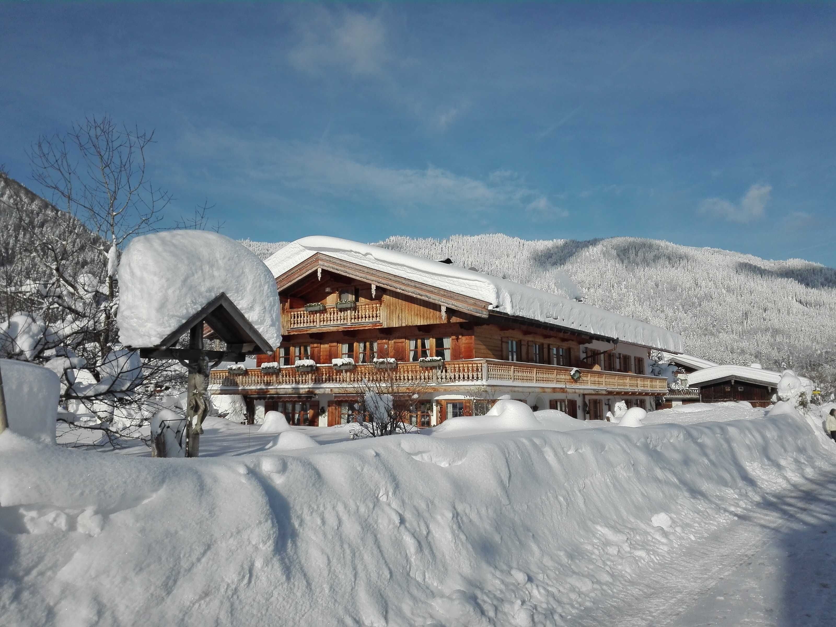 A wooden chalet with a balcony, surrounded by snow-covered hills.