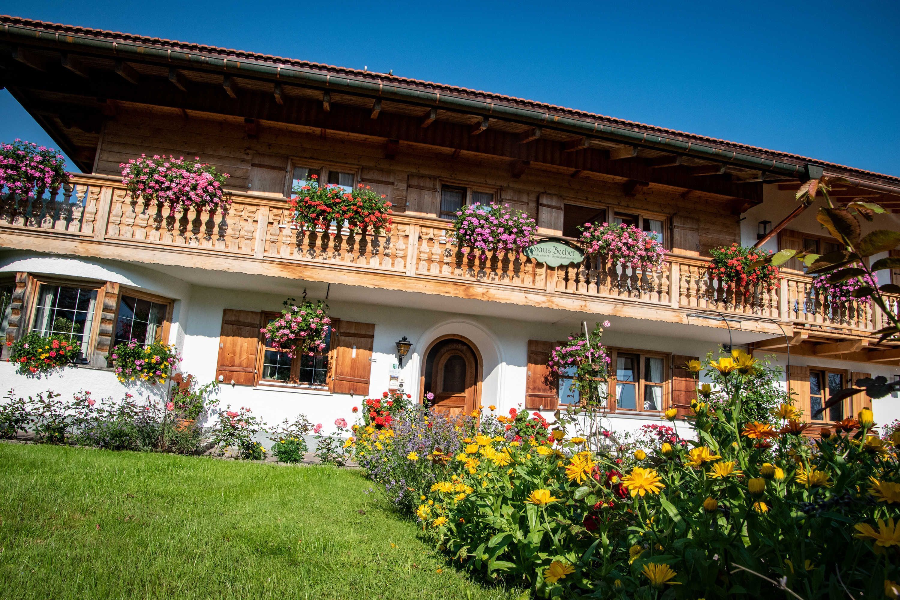 Ein traditionelles Holzhaus mit Balkonen, Blumenkästen und einem gepflegten Garten.