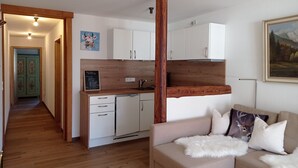 A compact living space with a kitchenette, a dining area, and a sofa with decorative pillows.