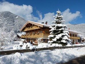 Un chalet en bois doté de balcons, entouré d’arbres et de montagnes couverts de neige.