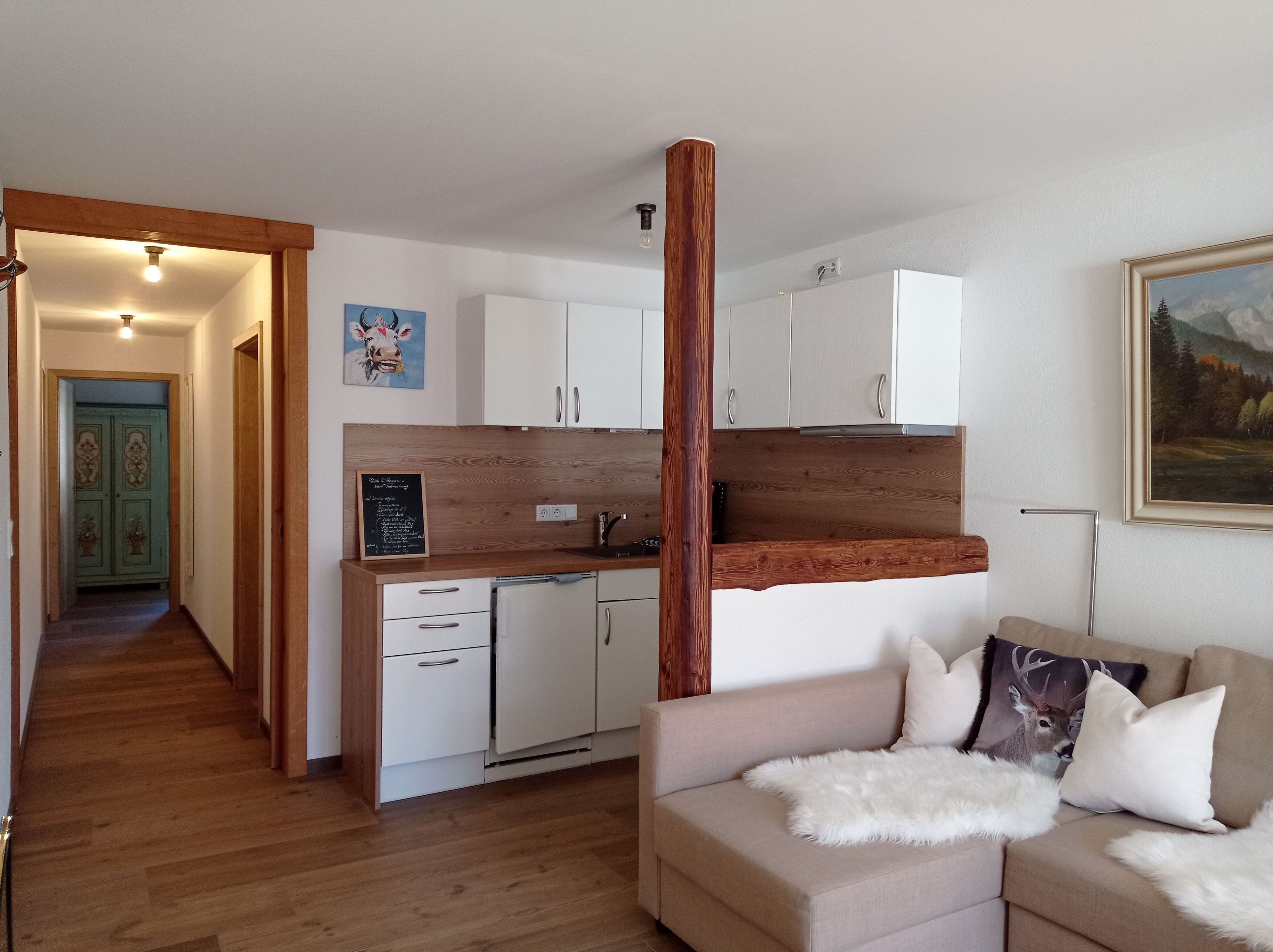 Een knus woongedeelte met een kitchenette, een eethoek en een bank met decoratieve kussens.