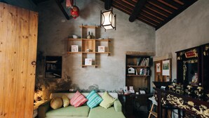 A cozy living room with a green sofa, wooden shelves, and a traditional altar. - Kinba Guest House (Jinning)