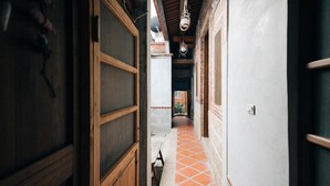 A narrow hallway with wooden doors and a tiled floor. - Kinba Guest House (Jinning)