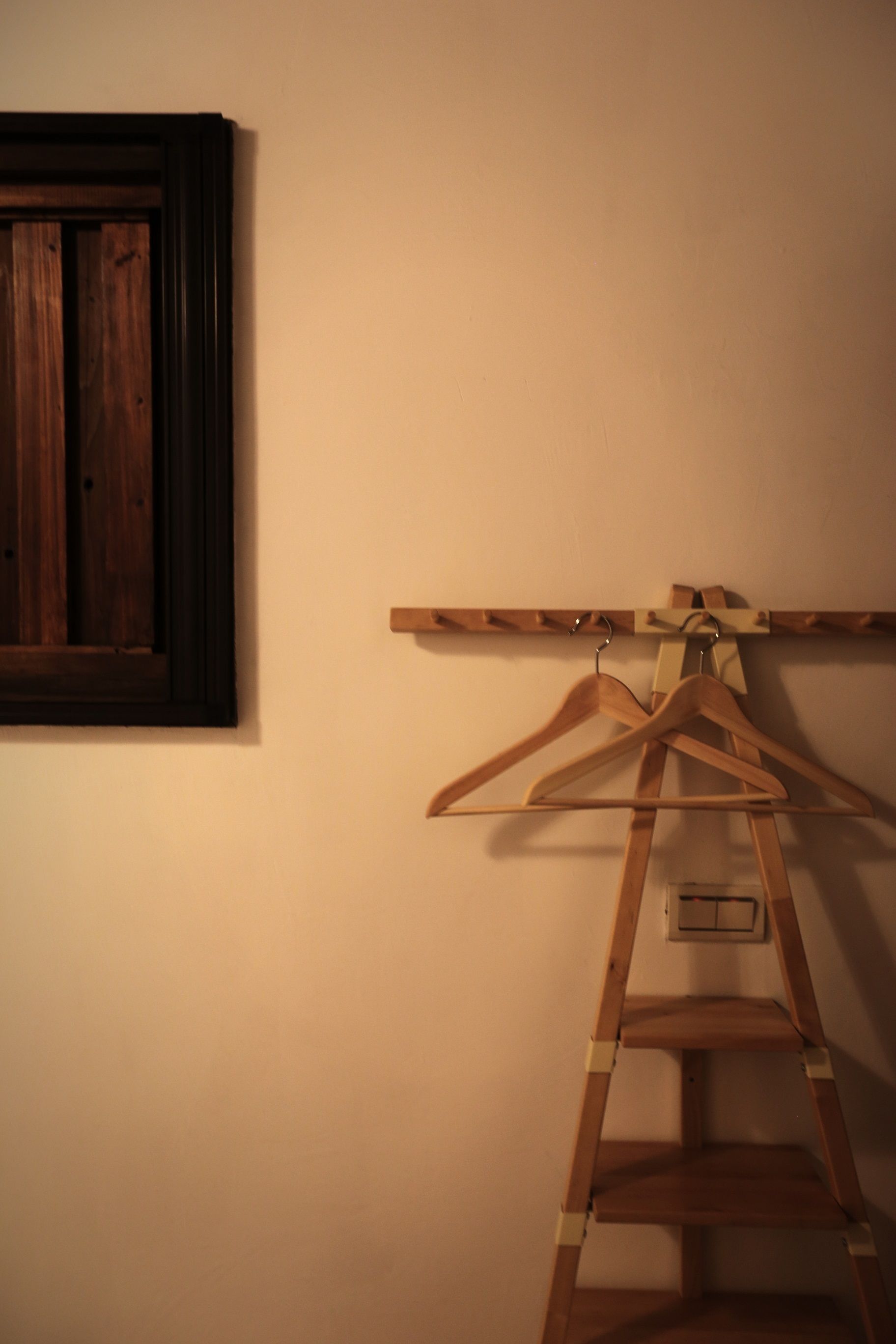 Una escalera de madera apoyada en una pared, con un perchero de madera encima.