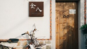 A wooden door with a sign above it, a metal light fixture, and a bicycle parked outside. - Kinba Guest House (Jinning)