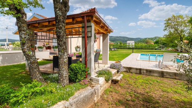 Un mirador de madera con piscina y zona de estar al aire libre.