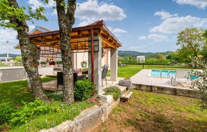 Un belvédère en bois avec une piscine et un espace salon extérieur.