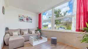 Un salón moderno con sofá, mesa de centro de vidrio y vistas al exterior.