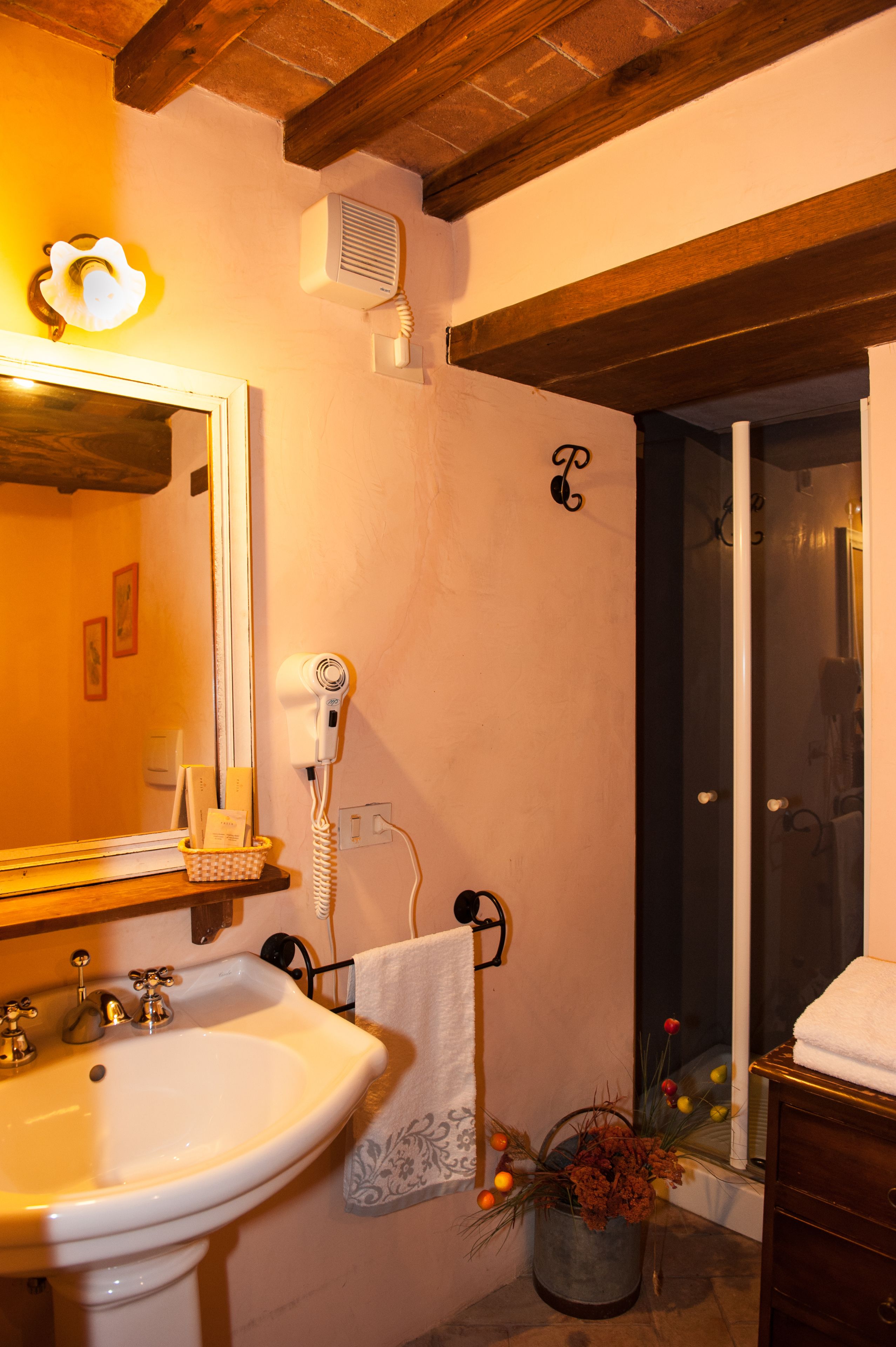 Un baño con lavamanos, espejo, toallero y zona de ducha.
