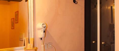 Un baño con lavamanos, espejo, toallero y zona de ducha.