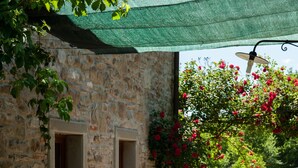 An outdoor dining area with a stone wall, two windows, and a table set with food and drinks. - Agriturismo Azienda Agricola il Pozzo (Capolona)
