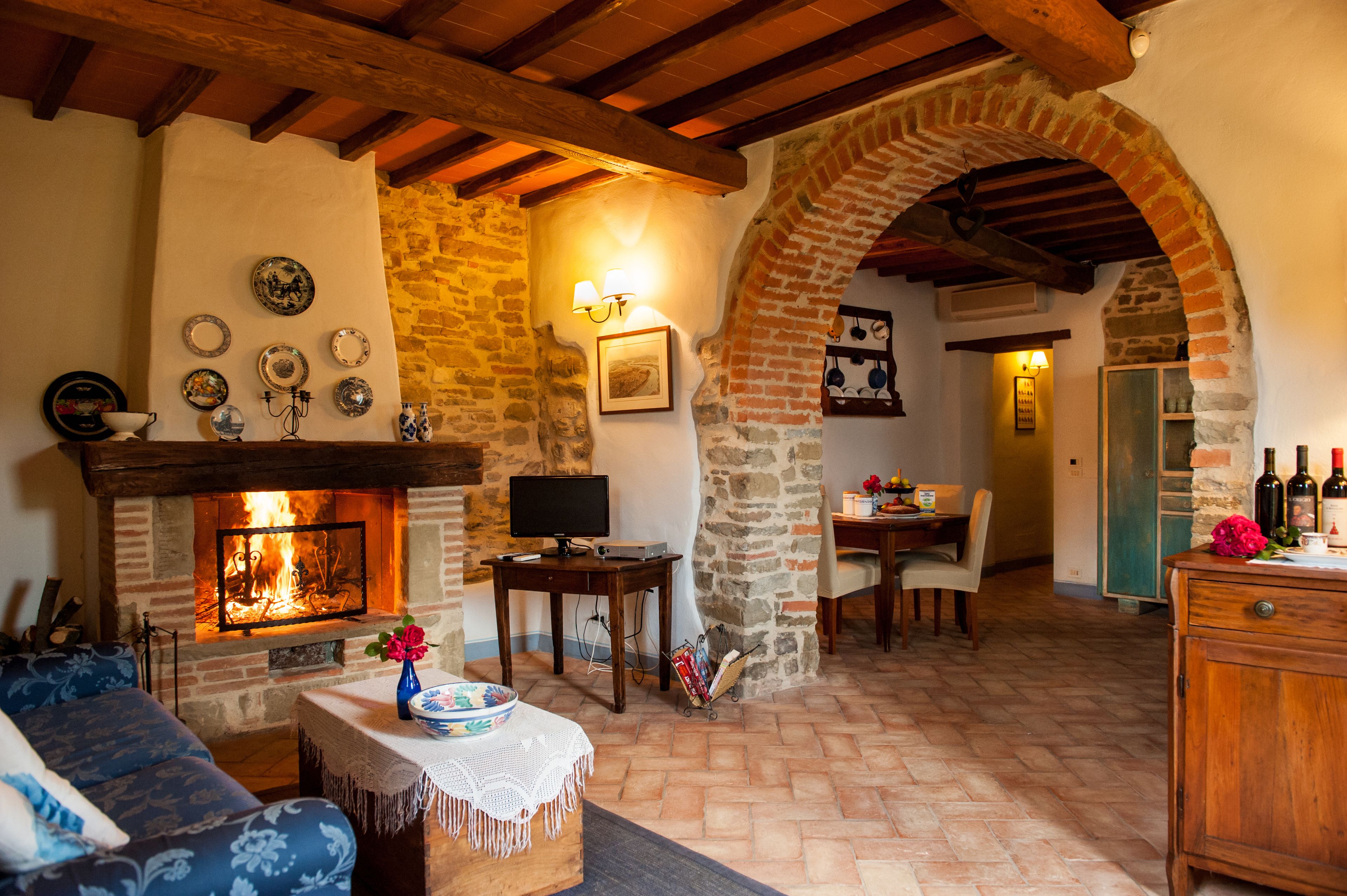 A cozy living room with a fireplace, stone walls, and wooden beams.