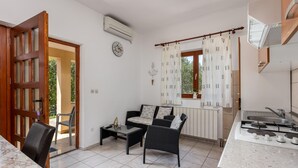Cozinha compacta com área de refeições, um sofá e uma janela com cortinas.