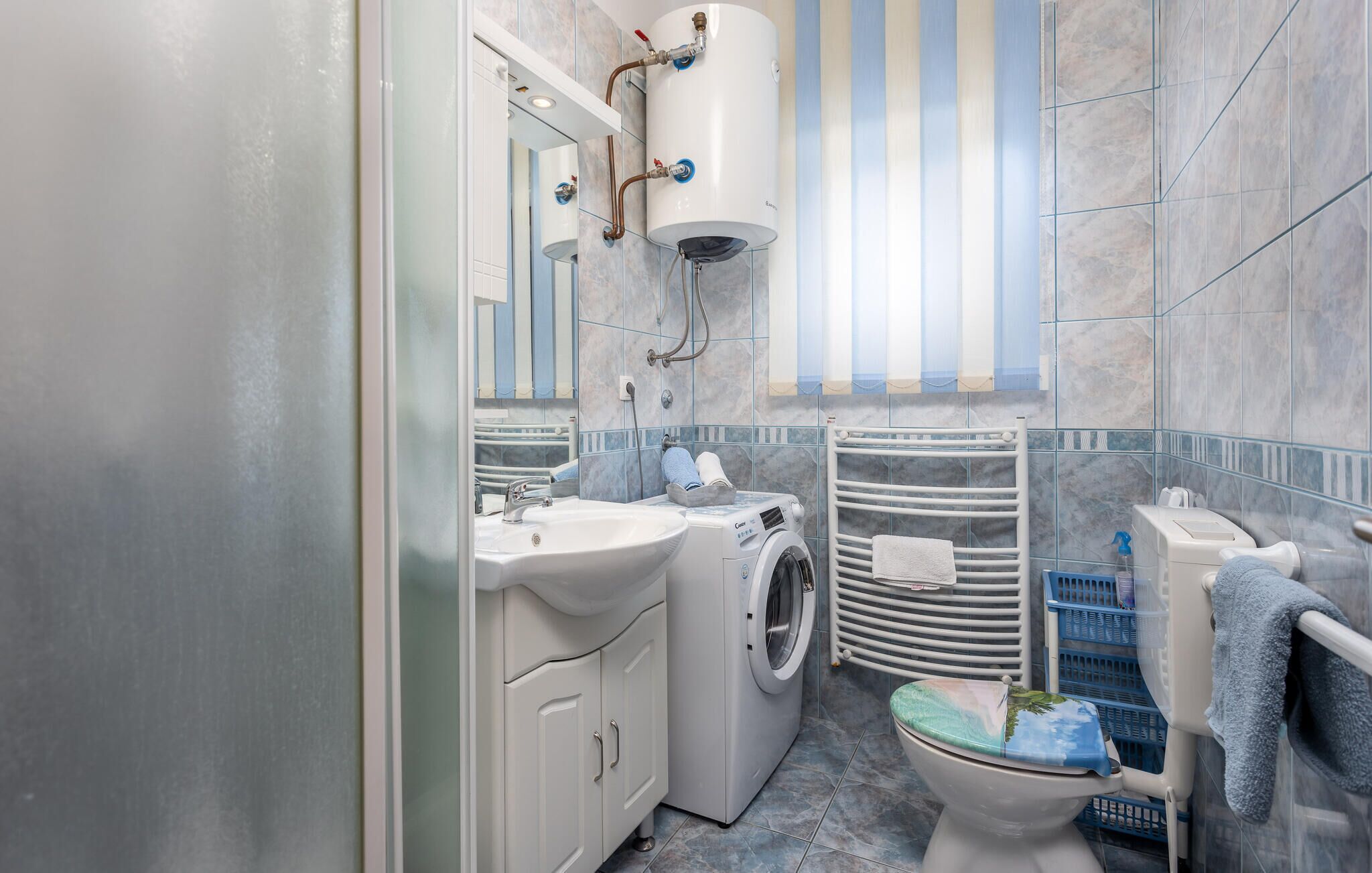 Ein modernes Badezimmer mit Waschmaschine, Toilette, Waschbecken und Dusche.