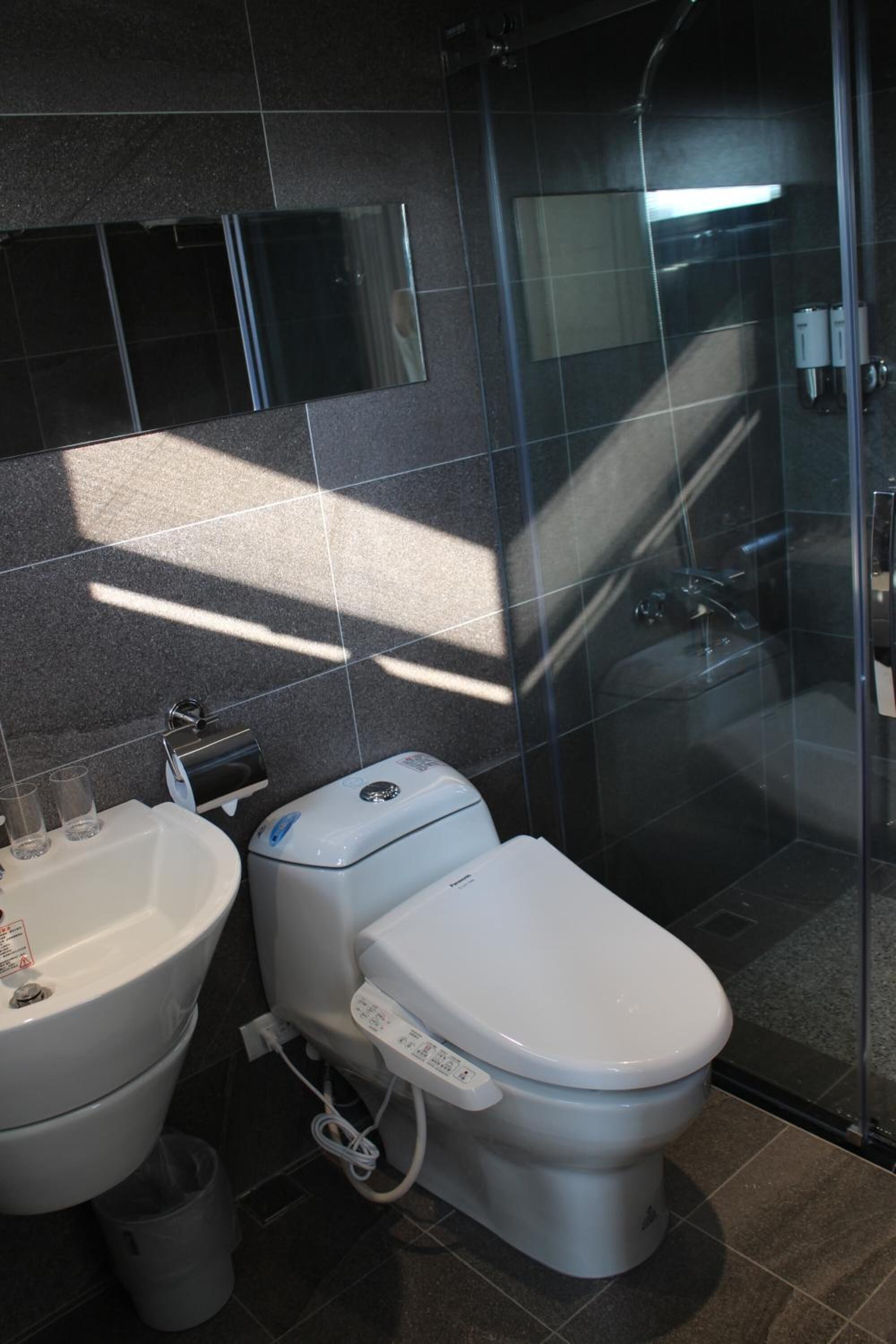 A modern bathroom with a toilet, sink, and glass shower enclosure.