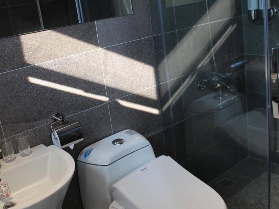 A modern bathroom with a toilet, sink, and glass shower enclosure.