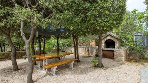 A covered picnic area with benches and a stone-built outdoor oven. - 1 bedroom amazing apartment in Mandre (Mandre)