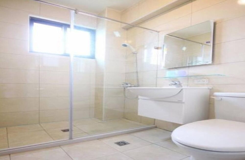Un baño con cabina de ducha de vidrio, lavabo e inodoro.