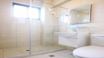 Un baño con cabina de ducha de vidrio, lavabo e inodoro.