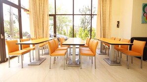 A dining area with tables and chairs, large windows, and a view of the outside. - Line In B&B (Jinhu)