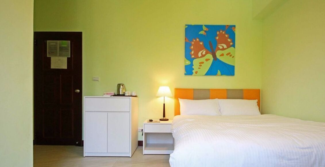 Una habitación de hotel con una cama, una mesita de noche, un escritorio y un cuadro en la pared.